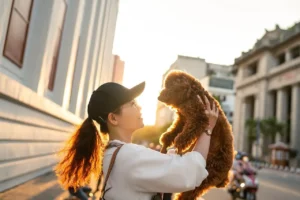 Frau hat Hund auf dem Arm und hält ihn hoch